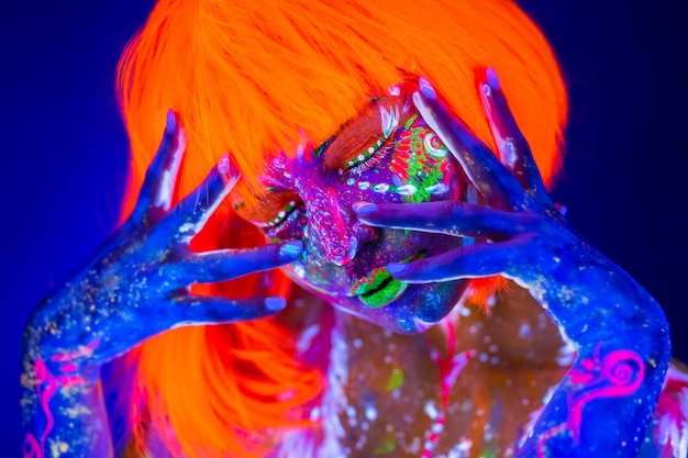 Foto neon donna che balla. modello di moda donna alla luce al neon, ritratto della bellissima modella con trucco fluorescente, arte in uv, trucco colorato