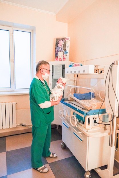 Neonatologist holding a newborn baby in his arms in the hospital