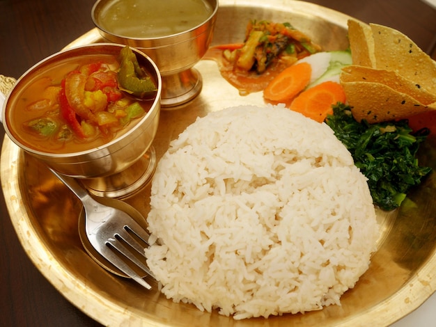 Nepalese local food set and water drinks on retro vintage brass plate set for serve lunch meal to nepali people and foreign travelers eat drink in dining room restaurant at thamel in Kathmandu Nepal