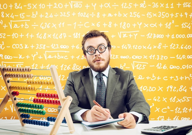 Nerd accountant does calculation of company revenue on yellow background