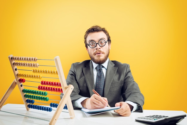 Nerd accountant does complex calculation of company revenue on yellow background