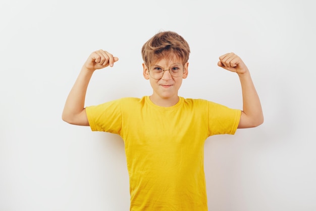 A nerd child with eyeglasses showing strength Yellow tshirt white background copy space Mockup for design