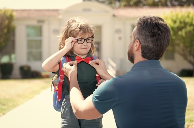 Nerd in glasses and bow tie with teacher outside the school education