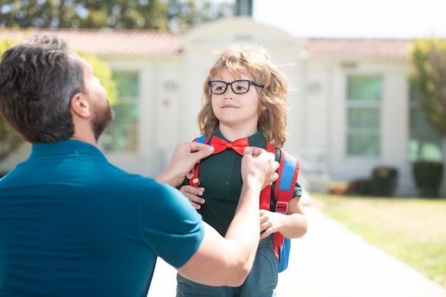 Nerd in glasses with teacher education first day at school\
father and son come back from school happy family value childhood\
and parenthood parent gathering small child boy to first grade