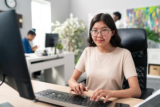 Nerd meisje met grote bril en t-shirt zit in een comfortabele stoel voor het bureau