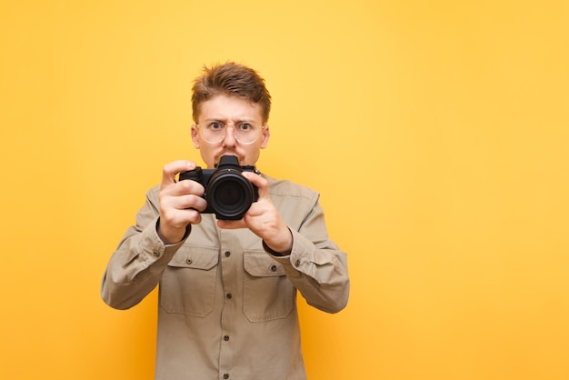 Nerd photographer in shirt and glasses takes pictures on digital camera