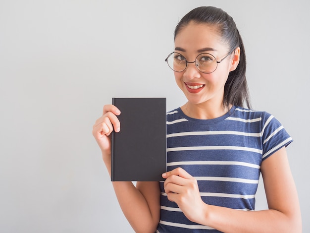 Photo nerdy asian woman smiles and holding a good book.