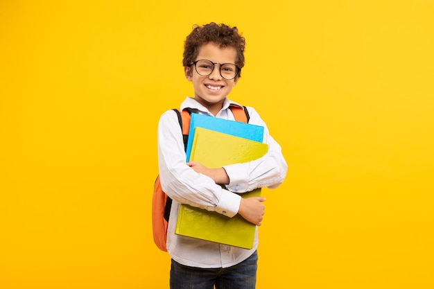 Nerdy boy with glasses holding books orange backpack