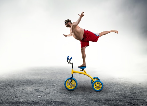 Nerdy man standing on a small bicycle