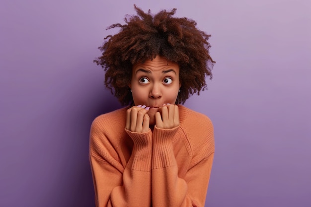 Nervous African American woman and biting nails in studio with oops reaction to gossip on purple