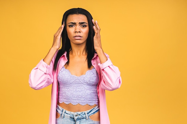 Nervous african american woman breathing calming down relieving headache or managing stress isolated on yellow background