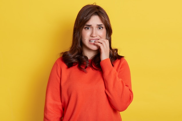 Nervous dark haired woman looking directly at front with frightened expression