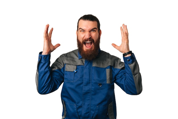 Nervous handy man wearing blue uniform screams and shows while gesturing