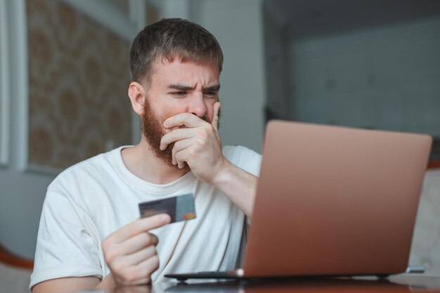 Nervous sad upset confused young man stressed worried guy having problem with paying buying online