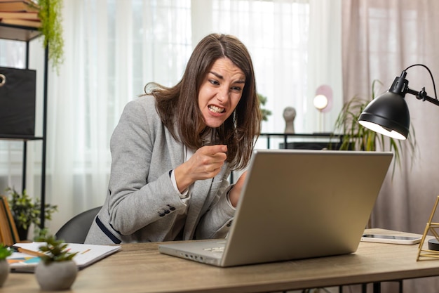 Nervous stressed businesswoman manager quarrelling laptop call online talking aggressively at office