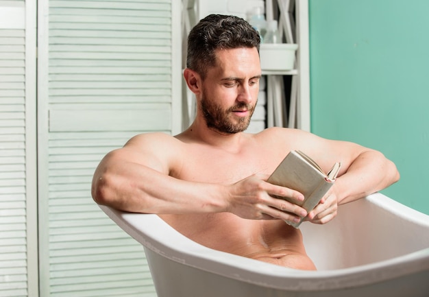 Nervous system benefit bathing Relax concept Man muscular torso relax bathtub and read book Relaxed guy reading book while relaxing in hot bath Relax at home Total relaxation Personal hygiene