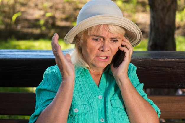 Nervous woman with phone senior lady wearing a hat must solve the problem no one can help