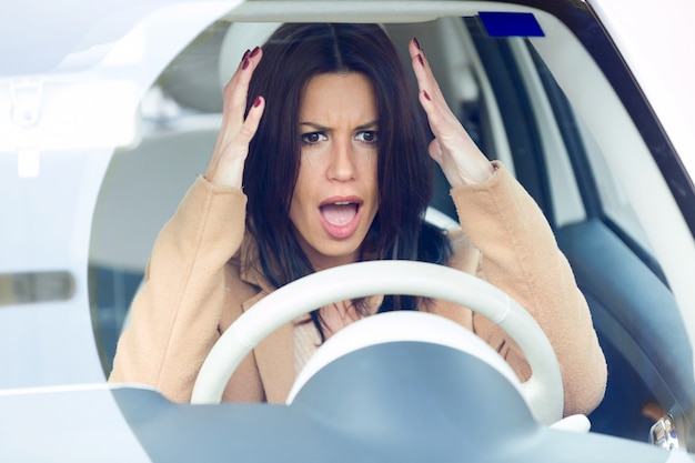 Nervous young businesswoman driving her car.