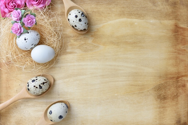 Nest eggs and flowers on wood background.