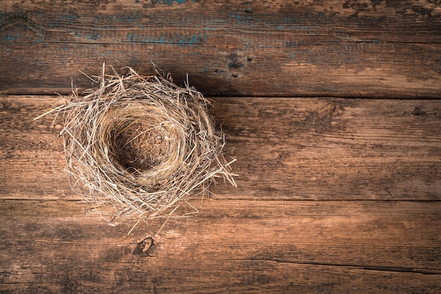 Nest gemaakt van droog gras op een natuurlijke houten achtergrond. Bovenaanzicht, horizontaal, met ruimte om te kopiëren.