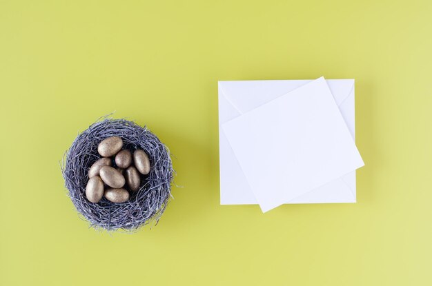 Nest met gouden eieren en witte kaart op gele achtergrond