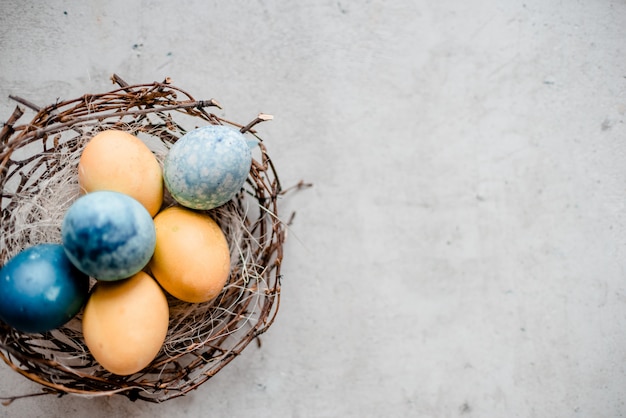 Un nido e diverse uova con bastoncini di salice. priorità bassa di pietra grigia astratta, concetto felice di pasqua