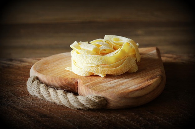 Nest van pasta tagliatelle op houten snijplank op rustieke achtergrond Selectieve aandacht