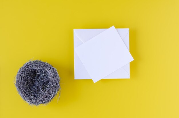 Nest with golden eggs and white card on yellow background