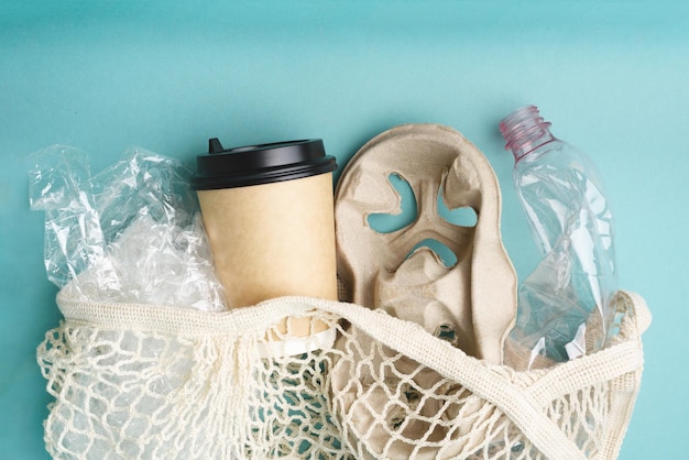 Net bag with plastic and paper rubbish on blue background