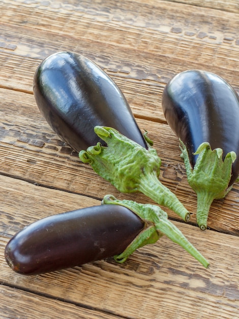 Net drie aubergines geplukt op oude houten planken. Net groenten geoogst. Bovenaanzicht.