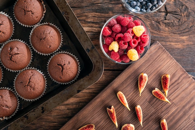 Net gebakken chocolade cupcakes in bakvormen en seizoensfruit en bessen Platliggend Bovenaanzicht