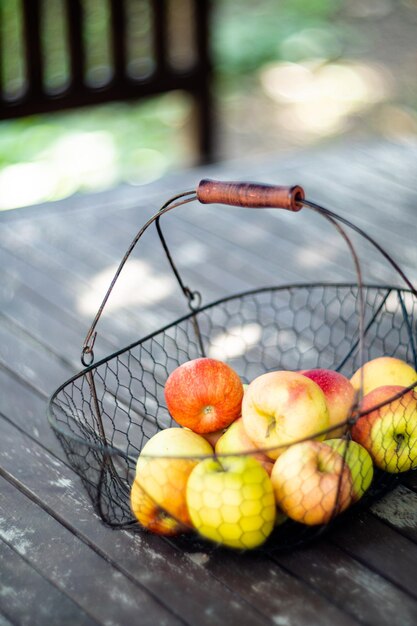 Net herfstappels geoogst in de metalen mand op houten tafel in de tuin