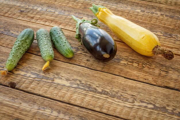 Net komkommers geplukt, een aubergine en een pompoen op oude houten planken