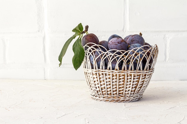 Net rijpe pruimen geplukt in een rieten mand op de witte achtergrond Net geoogste vruchten