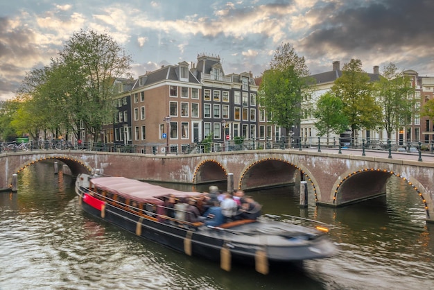 Netherlands Summer sunset on the canals of Amsterdam Pleasure boat floats between the bridges Traditional houses and bicycles on the waterfront