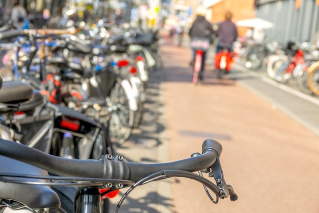 Photo netherlands. sunny day in amsterdam. bicycle parking and a couple of cyclists out of focus