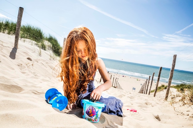 Нидерланды, Зандвоорт, рыжеволосая девушка играет на пляже