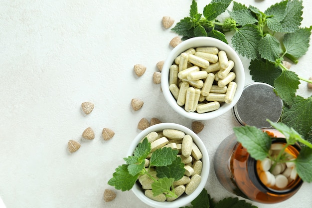 Nettle pills and ingredients on white textured table