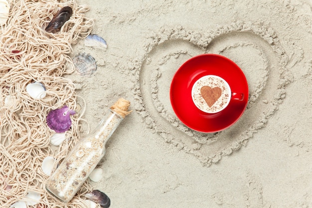 Netto, schelpen met fles en geschenkdoos met kop hartvorm op zand achtergrond.