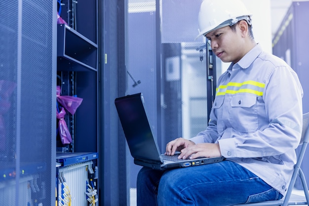 Netwerkbeheerder met laptop in de hand aan het werk Configuratie met kernschakelaar op rackkast in datacenter