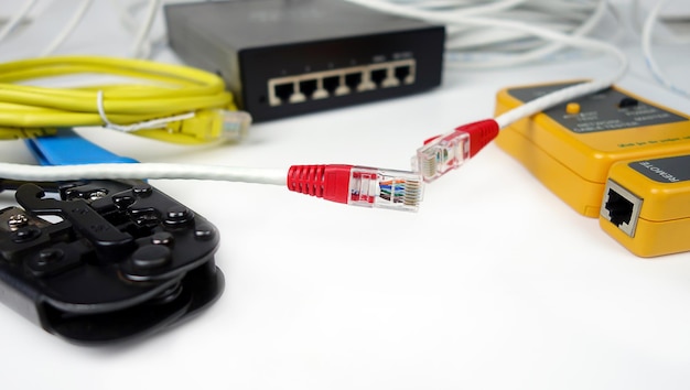 Foto crimpatrice per cavi ethernet switch di rete e tester per cavi rj45 isolati su sfondo bianco