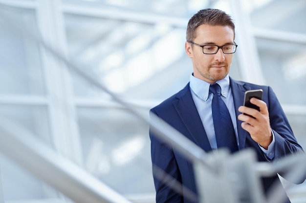 Foto networking aziendale o uomo d'affari con telefono per la ricerca su internet sui social media nella hall dell'hotel prima del viaggio in un aeroporto tech online o amministratore delegato sullo smartphone per la recensione o l'app del blog di viaggio