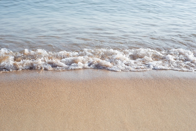 The neutral background of the sea surf. The wave hits the sand with bubbling foam. Soft focus