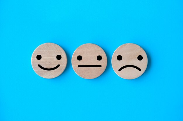 Neutral happy and sad emotion faces on wooden cubes customer satisfaction and evaluation concep