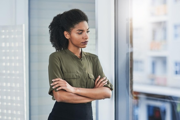 恐れや自己疑惑があなたの判断を曇らせないでください彼女のオフィスの窓の外を見ている若い実業家のショット