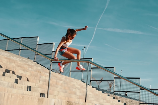 Never stop. Full length of beautiful young woman in sports clothing jumping while exercising outdoors