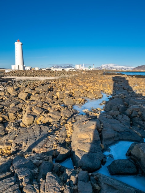 The new active Akranes lighthouse tower at end peninsula in city under blue sky Iceland