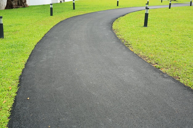 緑の草の庭の滑らかな道路の通路である新しいアスファルト。