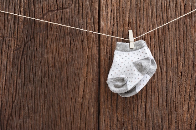 New baby socks hanging on clothesline over wood background newborn and baby concept