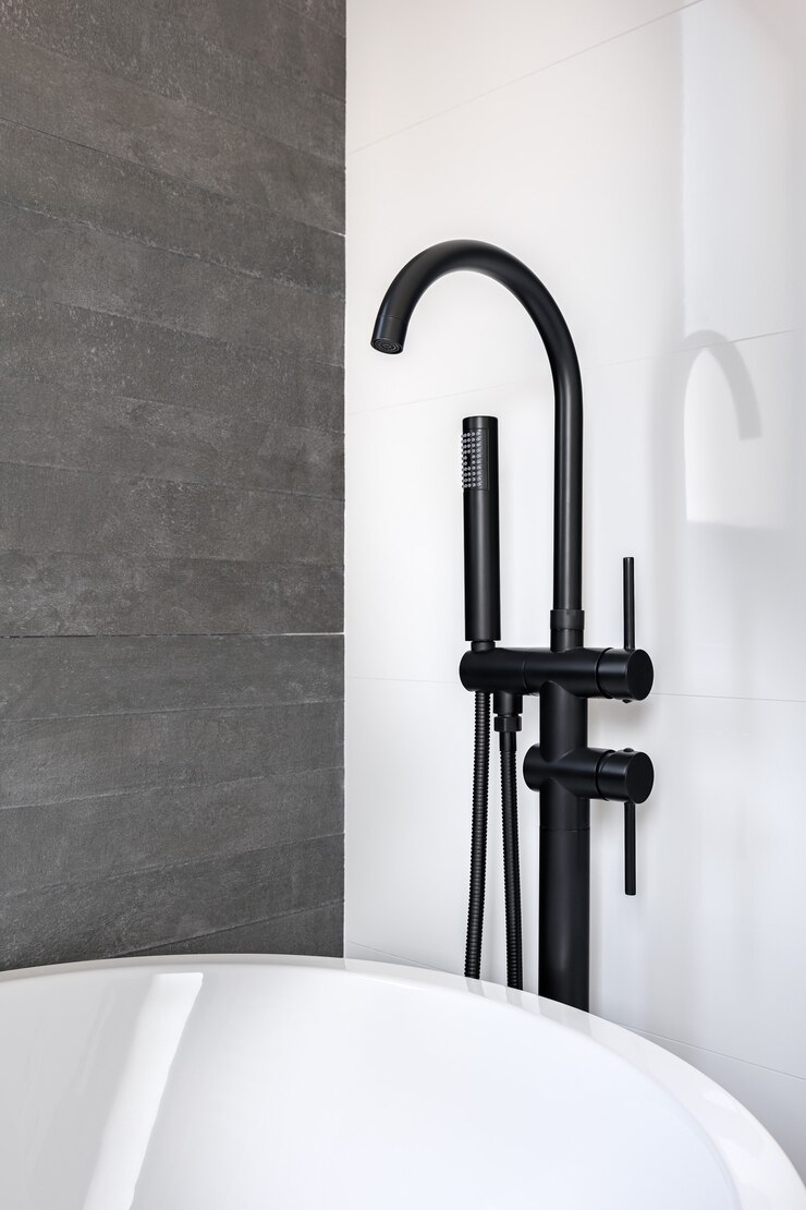 New black faucet and shower head against clean tiled white and gray wall of bathroom in modern apartment.